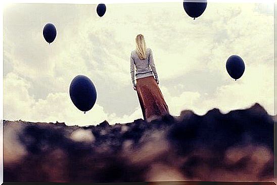 Woman looking at sky with black balloons