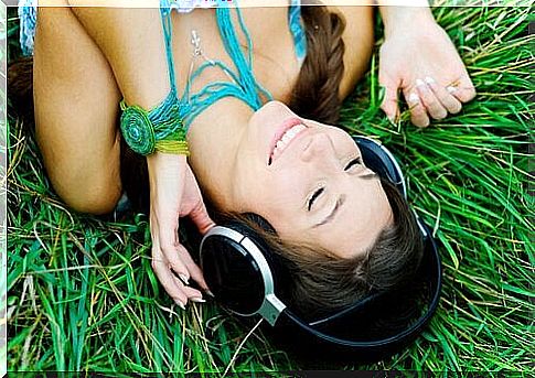 Girl lying on the grass listens to music with headphones