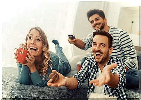 Friends sitting on a sofa watching a TV program