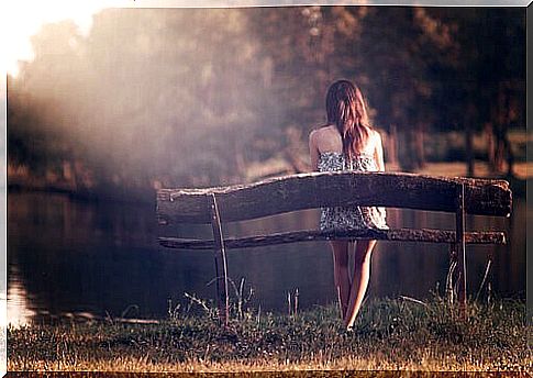 girl sitting on a bench in front of the lake